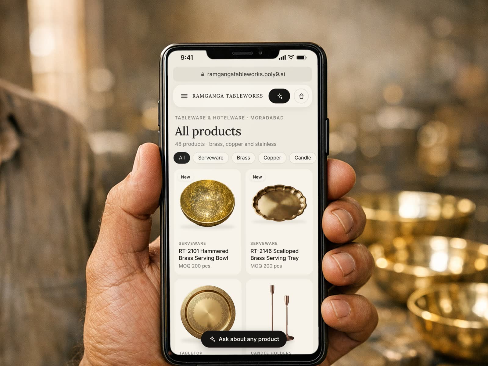 Hand holding a phone in a brass workshop, showing a sample Digital Booth product page, rendered