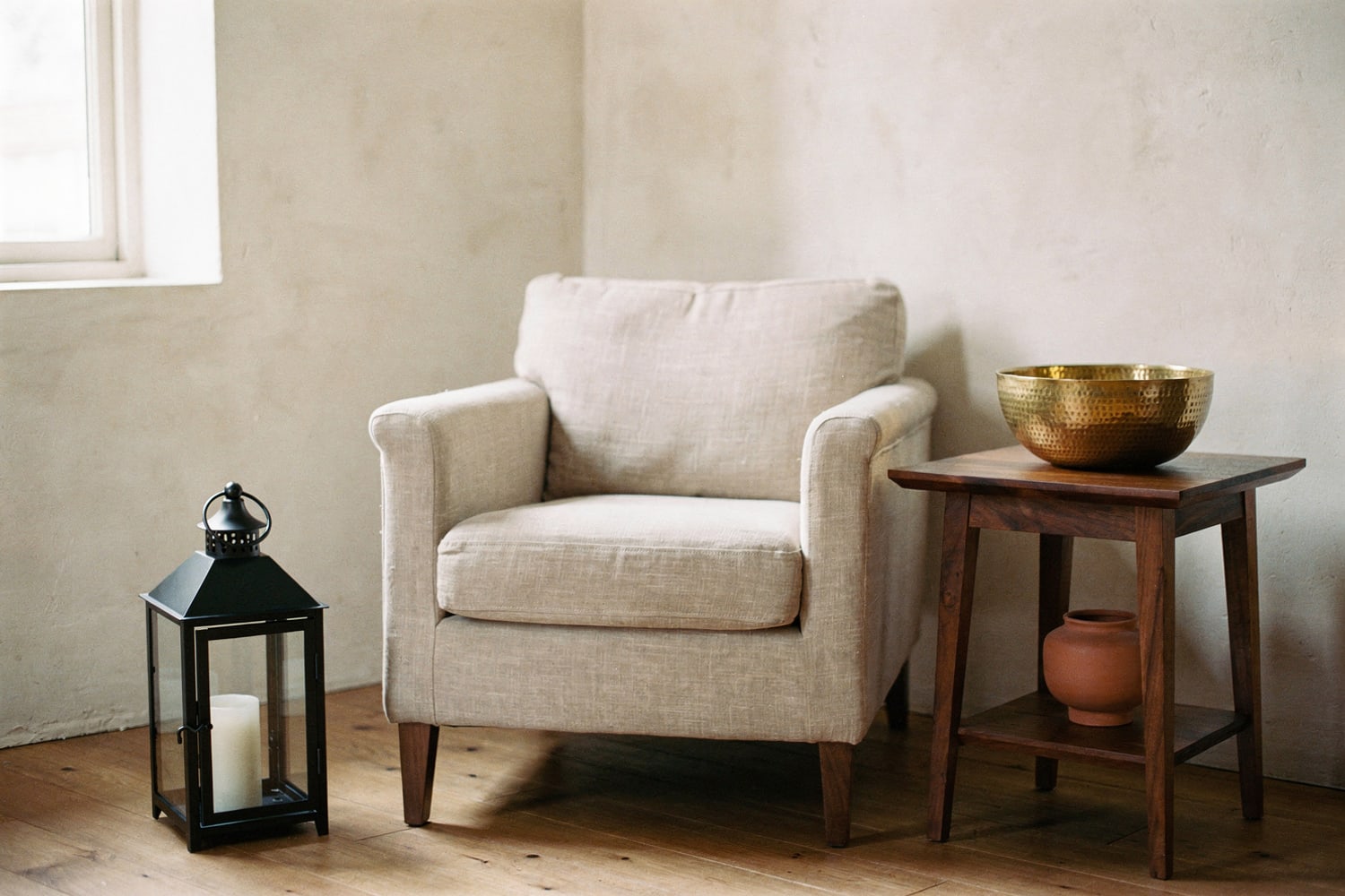 Iron lantern and brass bowl styled in a calm living room, rendered
