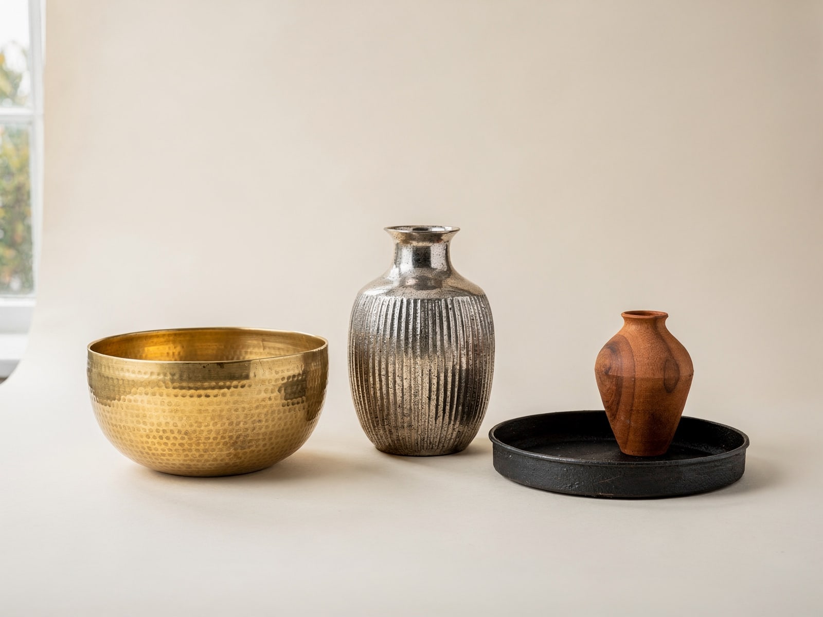 Textured brass and antique-nickel tabletop décor in mixed finishes, rendered