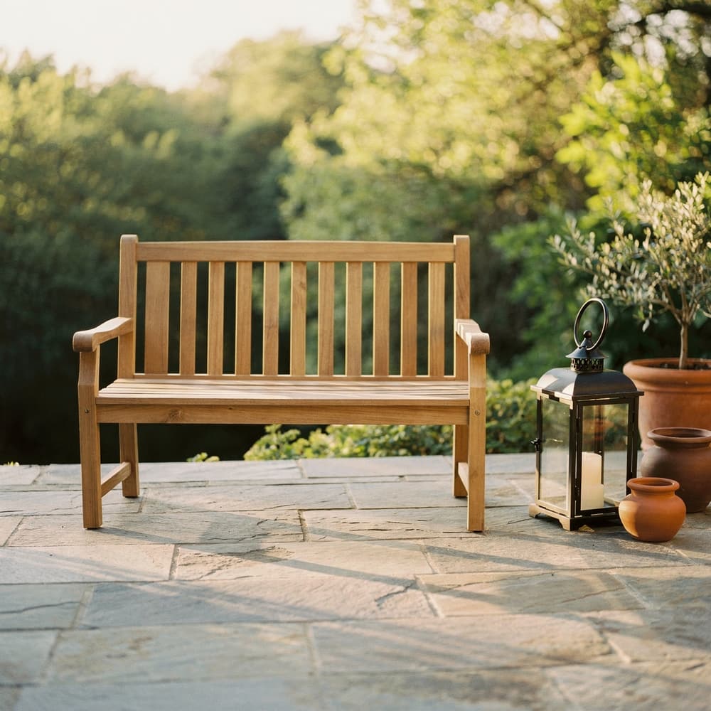 Teak bench and black iron lantern on a stone terrace at golden hour, rendered